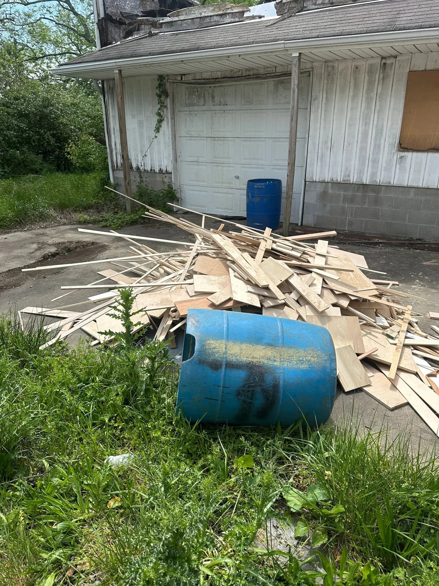 Pile of scrap lumber and construction debris beside a garage before removal